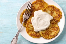 Plate of baked latkes with dollop of sour cream in the middle 